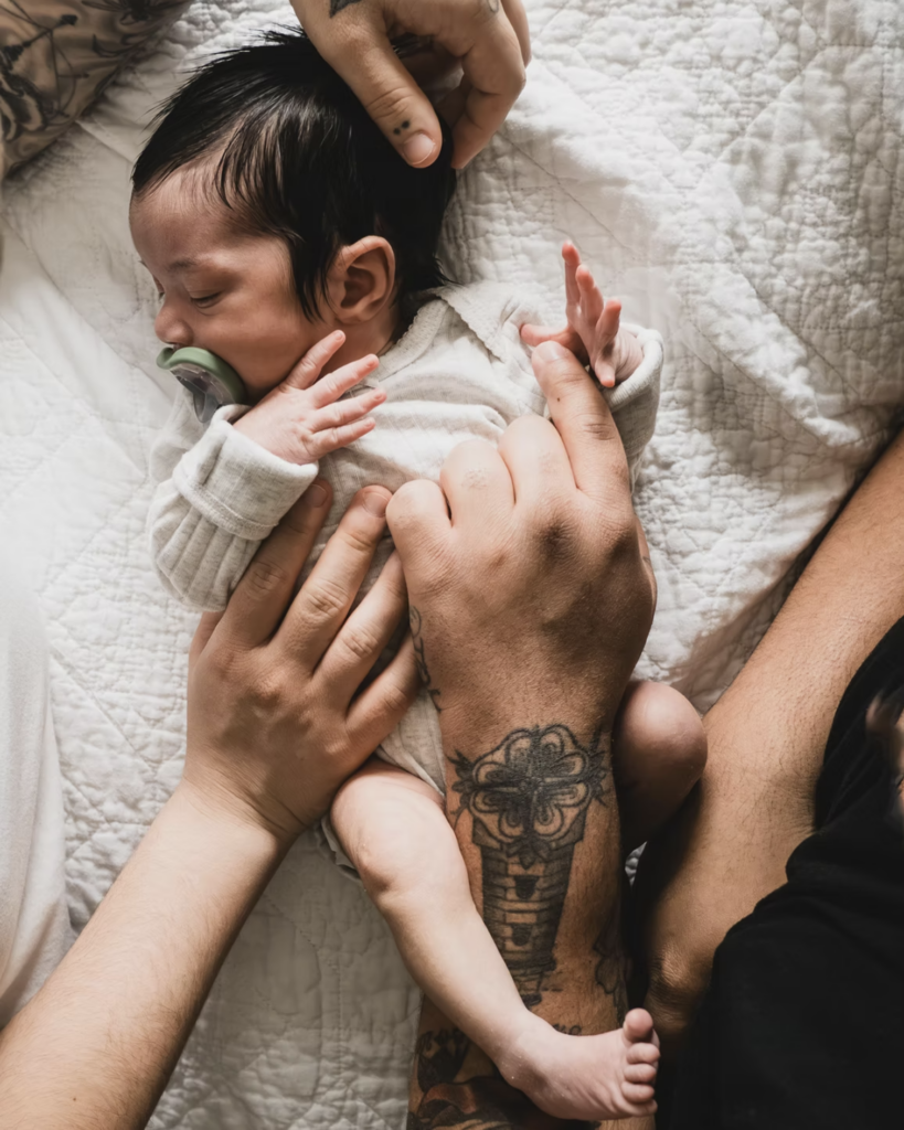 Portrait of a newborn baby with parents hands holding them.