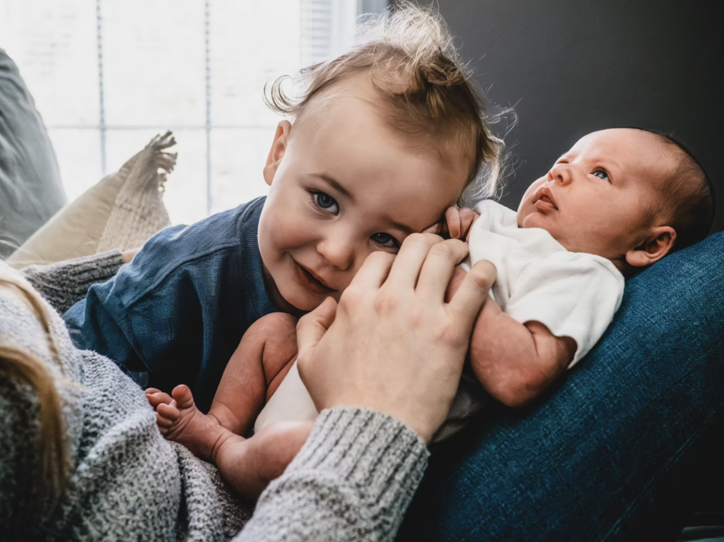 Sibling snuggles with new baby during lifestyle newborn session.