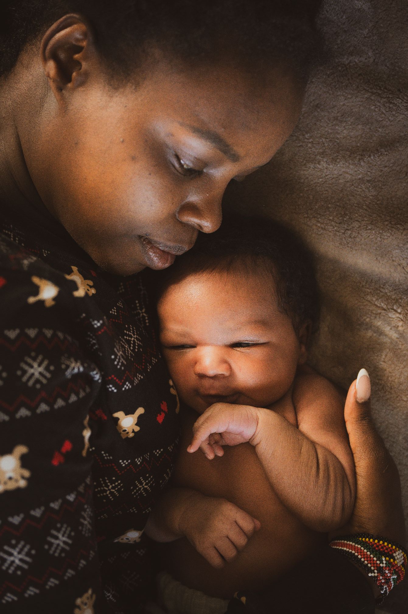 Top 10 finalist moody lifestyle portrait of a mother cuddled on the couch couch with her newborn.