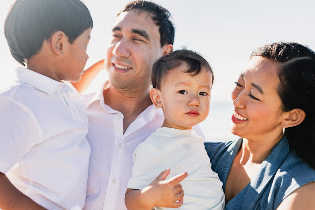 A mother and father holding their children close in natural light, showing how intentional family posing creates genuine connection and an effortless client experience.